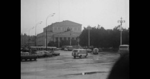 Cars moving fast speed in city street. Rush hour in town center. Urban road traffic. Transport motion on cityscape background. Archival vintage black white film. Old retro archive. 1980s Moscow Russia
