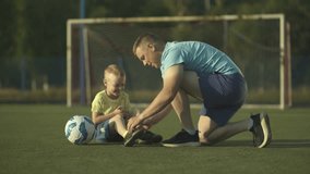 Father tying his little son's shoelaces on soccer field.  - Powered by Shutterstock - Get 15% off with code: PIKWIZARD15