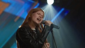 Young teenager girl singer performing on stage, contestant singing during recording of television style broadcast talent show - Powered by Shutterstock - Get 15% off with code: PIKWIZARD15