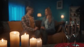 Glasses of champagne and a blurred loving couple in the background. A man and a woman in love are kissing while sitting on a sofa in the living room. Romantic evening, date. Slow motion. - Powered by Shutterstock - Get 15% off with code: PIKWIZARD15