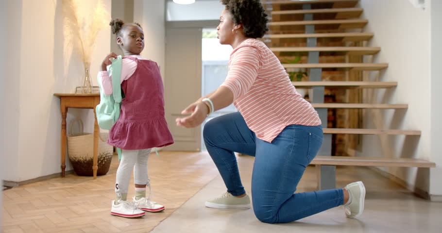Happy african american mother and daughter hugging at home, slow motion. Lifestyle, childhood, family, togetherness and domestic life, unaltered.