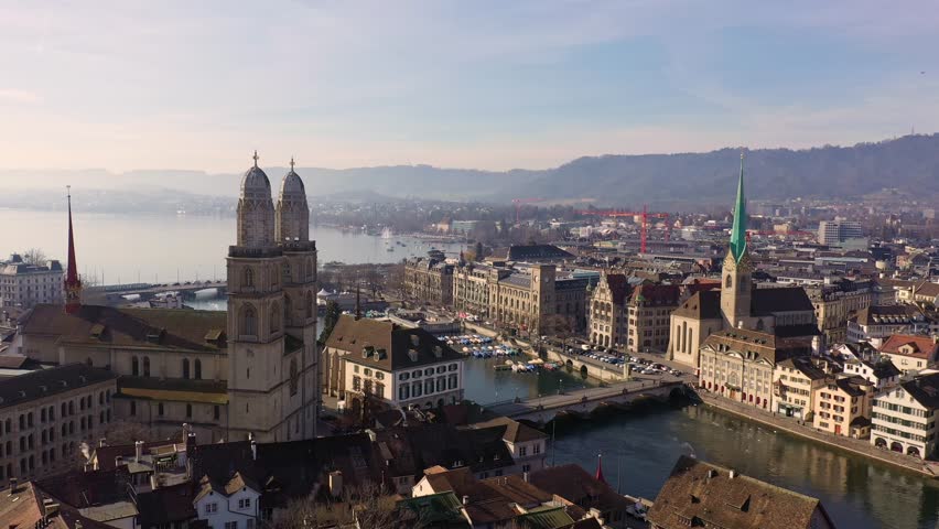 Zurich, Switzerland: Aerial drone footage of Zurich old town along the Limmat river the the Grossmunster cathedral in Switzerland largest city. 