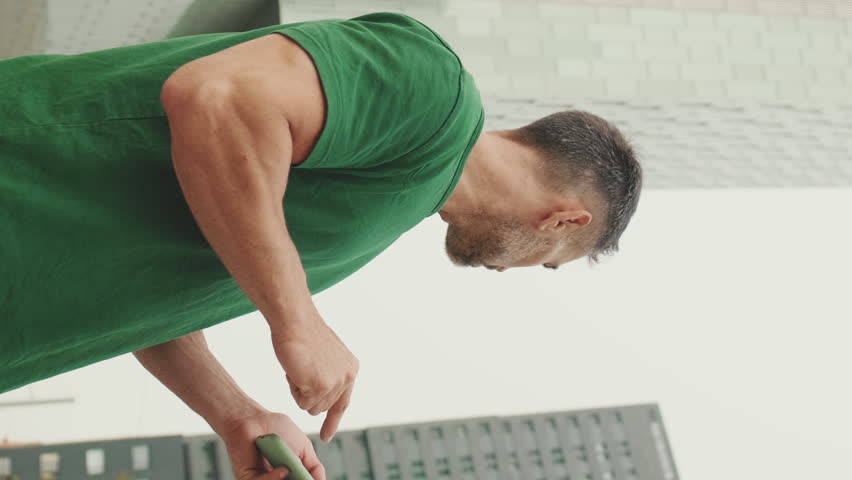 Vertical video, Mature male tourist wearing casual clothes, standing on modern buildings background, looking for right direction on smartphone, using map app, bottom view