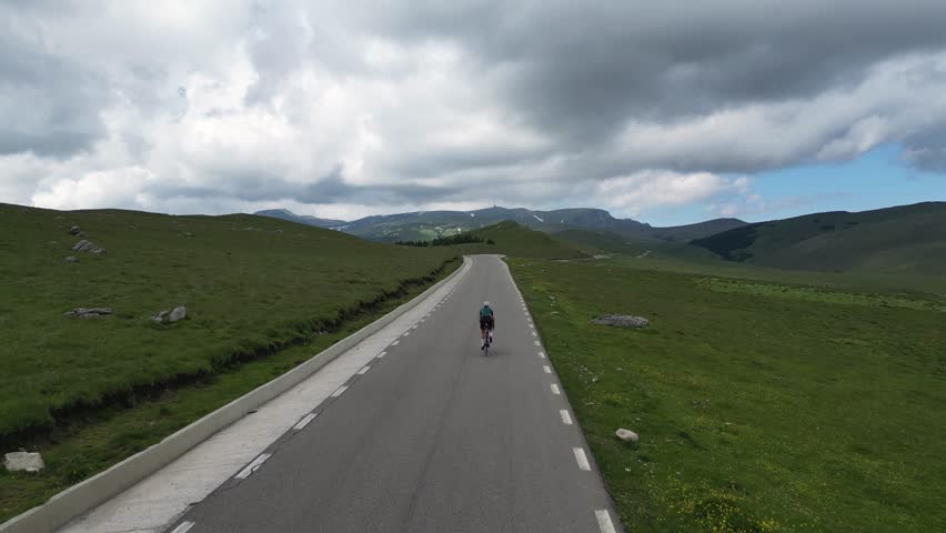 Female cyclist training in mountains. Pedaling through nature