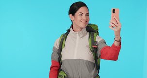 Video call, travel and woman tourist with cellphone in studio showing mockup space for marketing. Adventure, hiking and young female influencer on live stream with pointing gesture by blue background
