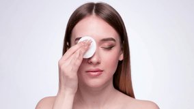 A young beautiful girl removes makeup with a cotton pad and micellar water from her face and eyes. - Powered by Shutterstock - Get 15% off with code: PIKWIZARD15