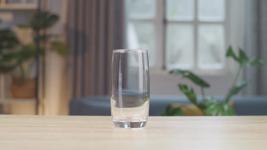 Fresh Milk Being Poured In To The Glass On The Table With Home Interior In The Background
