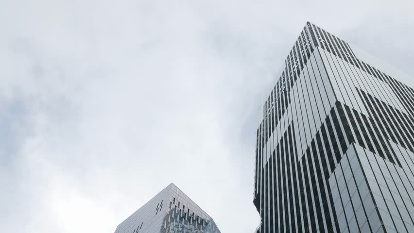 Look up to modern office high rise skyscraper financial buildings in city central business district. Looking up at modern glasses buildings up to sky with clear sky in background Royalty-Free Stock Footage #1105970343