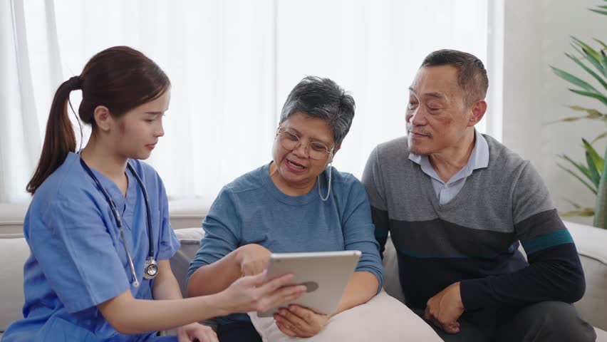 Asian female nurse caregiver is describing the patient's condition on tablet. Homecare nursing service and elderly people health care. Elderly care concept | Shutterstock HD Video #1105971347