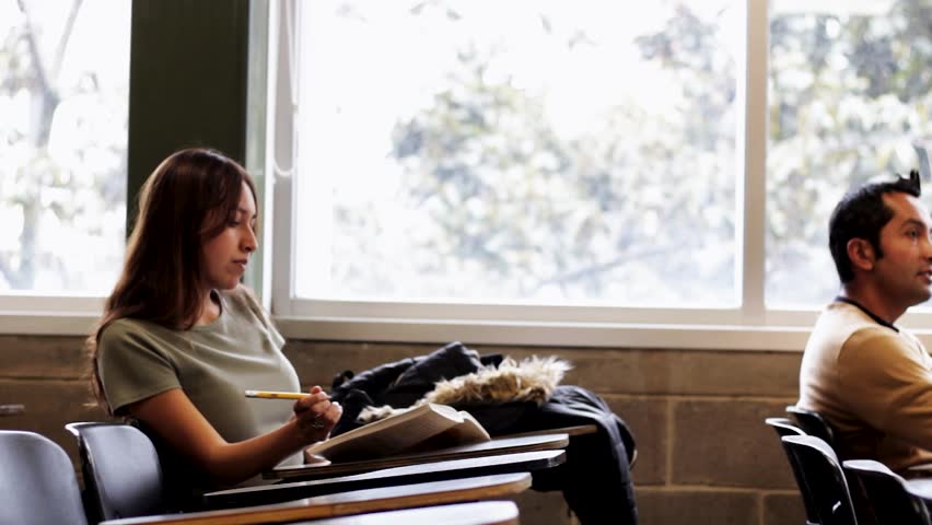 Happy Hispanic generation Z student woman studying in a classroom at a Colombian university on a study research project, holding a learning book, notebook, headshot portrait
