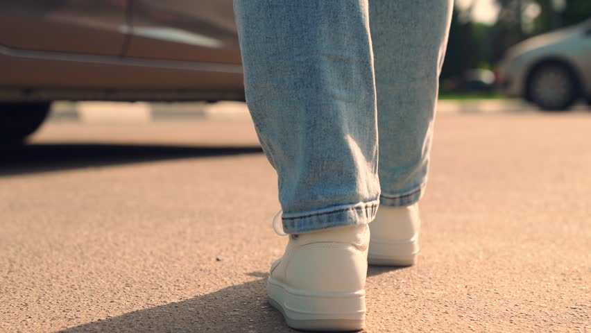 Legs man, woman walk to car close-up. Man get in taxi day. Guy, girl in white sneakers get in car in parking lot. Woman driver open door car, get in auto. Rear view legs man getting in car close-up Royalty-Free Stock Footage #1105973909