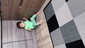 One year old toddler sitting on the kitchen shoving his feet cheerfully. Kid eating a snack. Vertical video.