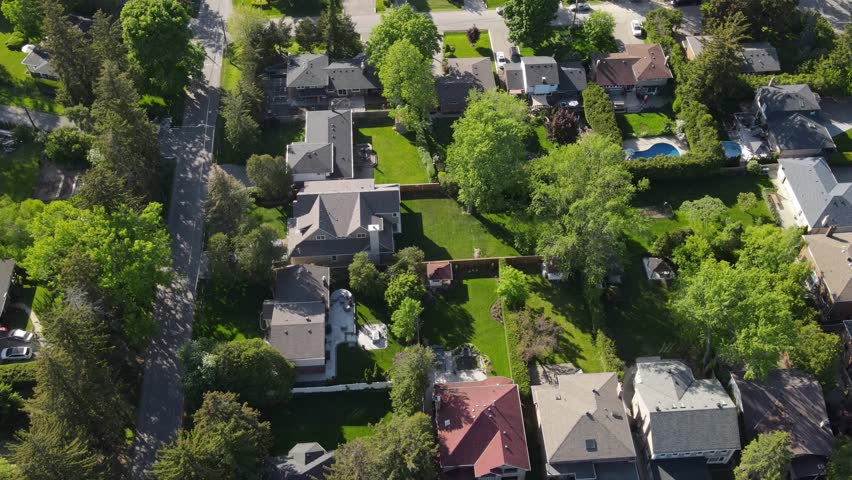 Aerial view of residential buildings in summer. North American area, suburb. Real estate, drone footage, sunset, sunlight, view from above. Small green city, suburb. Roofs of cozy houses, many trees. Royalty-Free Stock Footage #1105977439