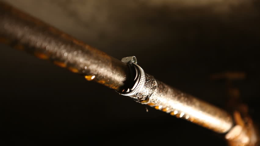 A male plumber puts a metal clamp on a water pipe. A man in the basement, repairing a water pipe from leaking. Royalty-Free Stock Footage #1105979019