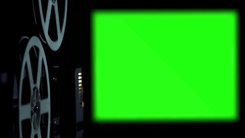  Old Cinema Projector Displays Green Screen. In a dark room you can see parts of the film projector and his wheels that turn. – Video có sẵn