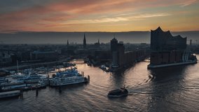 Establishing Aerial View Shot of Hamburg, Germany, incredible morning, mix of light fog and wonderful red yellow sky, HafenCity, Speicherstadt, Mitte, Altstadt, track in push in, small boat passing by