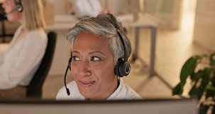 Call center, talking and senior woman on video in office for customer service, support or crm. Webinar, telemarketing and happy sales agent, professional or business consultant with deadline at night