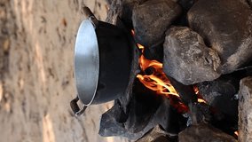 vertical video improvised campfire with stones and wood in a camping pot on the fire