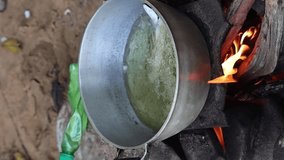 vertical video Fish being fried in oil in a metal pan over a campfire