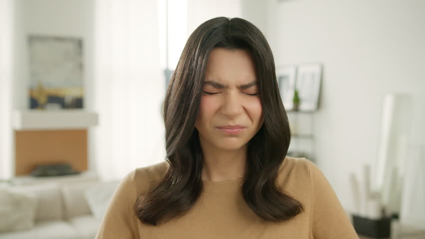 Series of face emotions, anxiety pain pressure, mental stress, panic attack, aching sore head. Frustrated stressed upset brunette woman coping with headache migraine at home. Painful headache concept | Shutterstock HD Video #1105985185