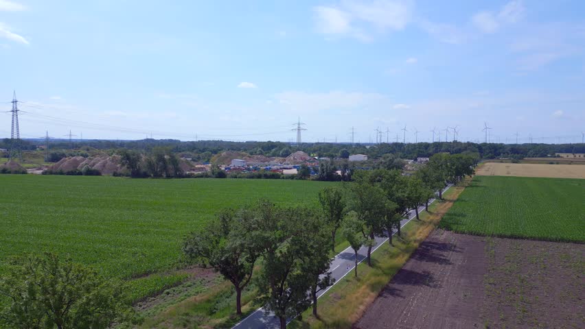 cyclist on country road alley. Gorgeous aerial top view flight red poppyfield Rural area summer meadow. Brandenburg Havelland Germany 2023. overflight flyover drone
4K cinematic.