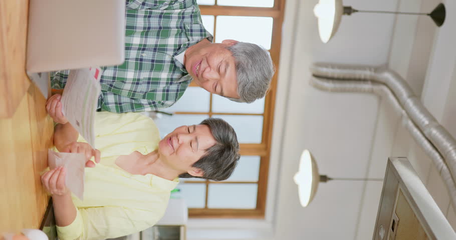 Close up vertical view of asian elderly couple happily reading bills in the kitchen - a well managed with financial planning retirement life style Royalty-Free Stock Footage #1105993681