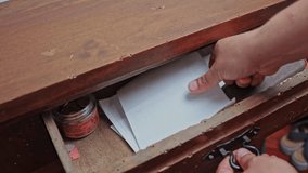 A man's hand opens the drawer of an old chest of drawers, puts the document inside. - Powered by Shutterstock - Get 15% off with code: PIKWIZARD15