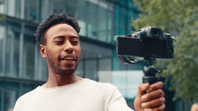 Young man travelling through city recording travel vlog on video camera - shot in slow motion