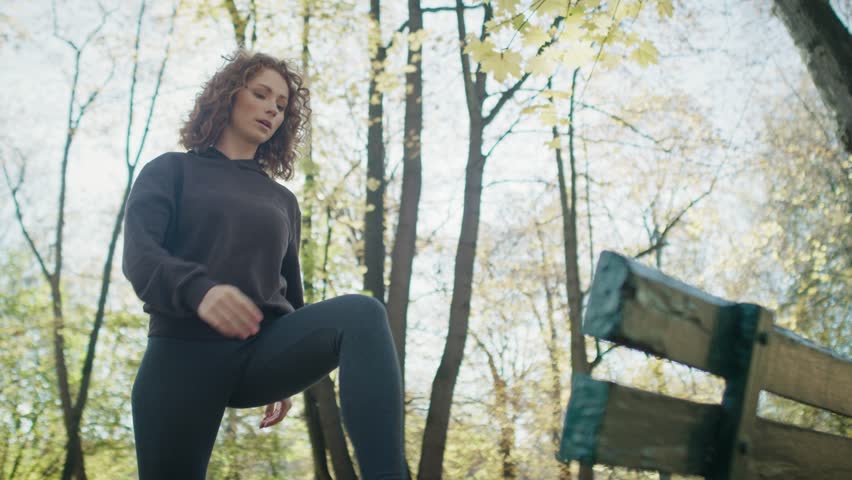 Ginger woman warming up before running at the park in autumn. Shot with RED helium camera in 8K. 