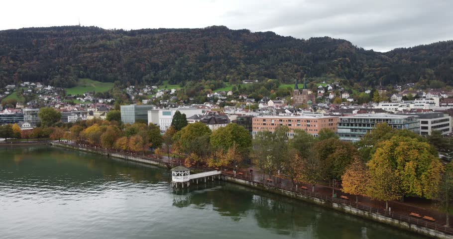 Beautiful city of Bregenz with its alpine buildings on the edge of a lake Constance with its calm rippling water and its gazebo in the middle of the Austrian alps, aerial view