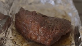 This video shows savory juice splattered on top of brisket steak meat in slow motion.