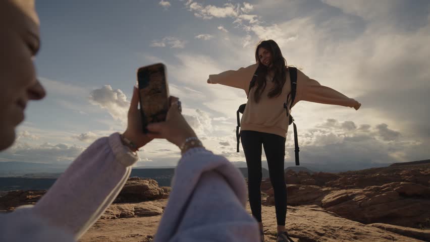 Over the shoulder low angle view of woman photographing hiker friend in rocky landscape, snow canyon, utah, united states Royalty-Free Stock Footage #1106009361