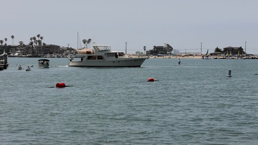Footage of a beautiful summer landscape at Horny Corner Beach with people relaxing on the beach surrounded by boats and yachts, cars and lush green palm trees in Long Beach California USA