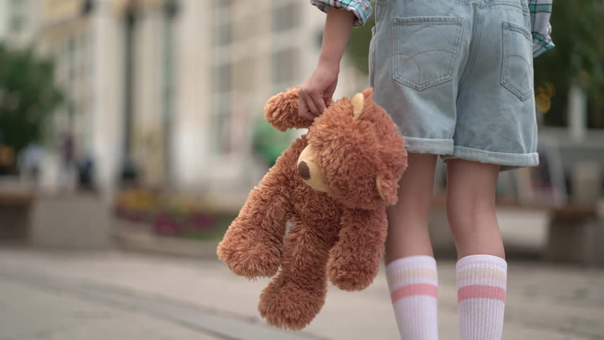 close-up of the kid leg walks with toy bear. Girl with teddy bear in his hand on walk Royalty-Free Stock Footage #1106012845