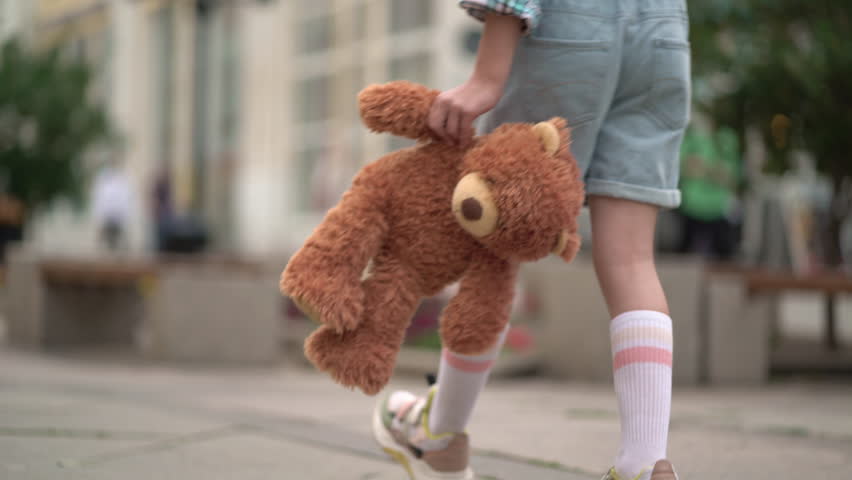 close-up of the kid leg walks with toy bear. Girl with teddy bear in his hand on walk Royalty-Free Stock Footage #1106012845