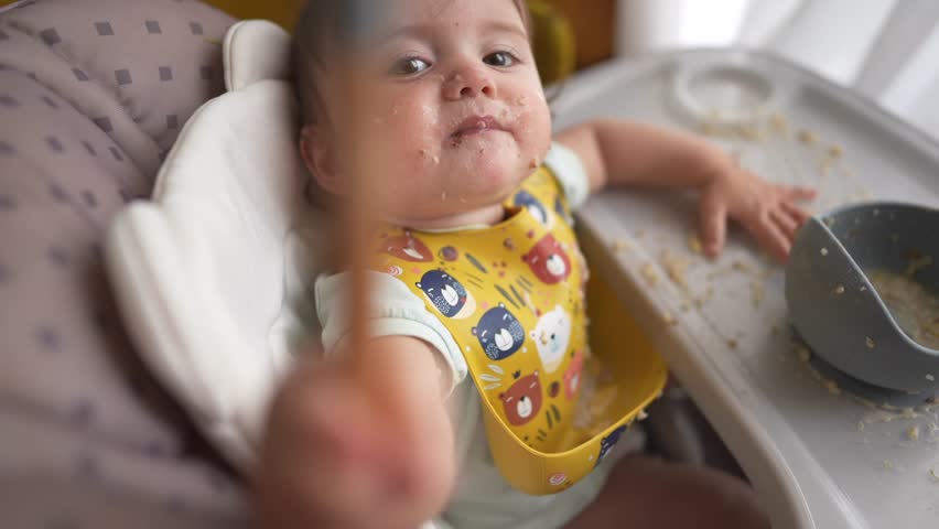 baby dirty eats. happy family toddler concept. baby girl learns to eat with her hands dirty her face dirty funny video. dirty baby on the table for feeding eats with dream her hands from cup Royalty-Free Stock Footage #1106014347