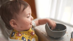 baby dirty eats. happy family toddler concept. baby girl learns to eat with her hands dirty her face dirty funny video. dirty baby on the table for feeding eats with her hands from cup dream