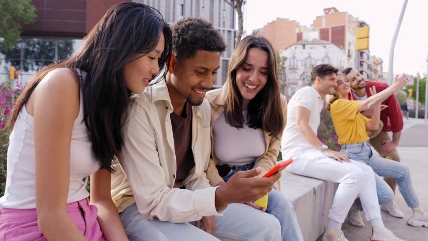 Multiracial happy group of friends using phone and smiling together outdoor. People addicted to technology and social media. Fun young and networks as means of communication. Royalty-Free Stock Footage #1106014541
