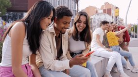 Multiracial happy group of friends using phone and smiling together outdoor. People addicted to technology and social media. Fun young and networks as means of communication. - Powered by Shutterstock - Get 15% off with code: PIKWIZARD15