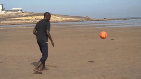 Video portrait of a male, person of color, in his thirties, playing football at the beach in Morocco, north africa