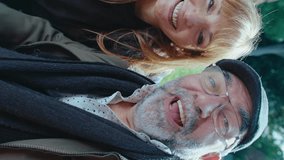 Positive senior couple looking at camera, waving and chatting with relatives on video call outdoors in the park. Vertical clip, POV shot - Powered by Shutterstock - Get 15% off with code: PIKWIZARD15