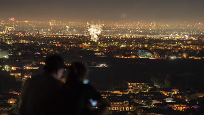 Couple in love are watching fireworks from mountain during Independence Day in Las Vegas, Nevada. 