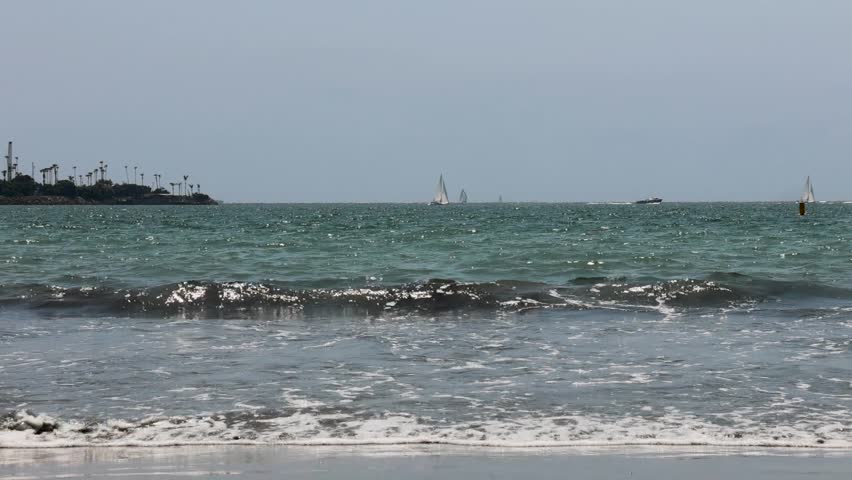 footage of the vast blue ocean water with waves rolling in and sailboats and motorboats sailing across the water with blue sky Rosie’s dog beach in Long Beach California USA	