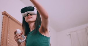 Young woman having fun playing games while wearing virtual reality glasses at home.