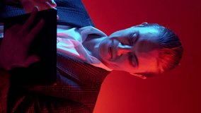 Vertical video. Digital business. Information technology. Blue red color neon light curious satisfied man using tablet on dark free space background. - Powered by Shutterstock - Get 15% off with code: PIKWIZARD15