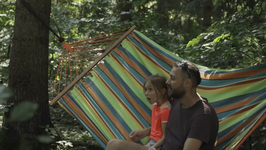 Family moments. Father and little daughter spending time together in a hammock in nature