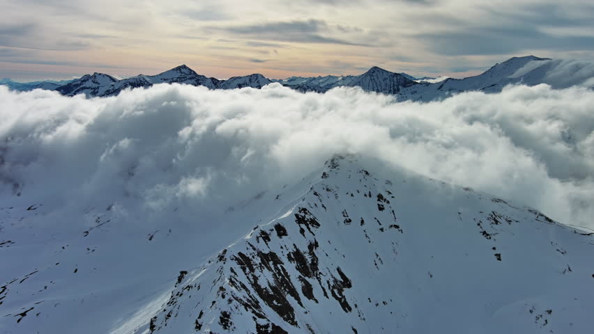 Aerial around view of snow mountain range landscape with clouds. Alps mountains, Austria, 4k