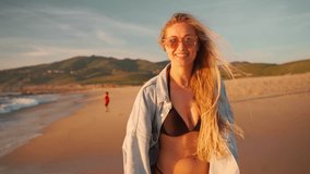 Cheerful happy woman running on ocean beach with mountains background. Playful female tourist in bikini and denim shirt spinning, smiling looking camera. Vacation on sea shore  - Powered by Shutterstock - Get 15% off with code: PIKWIZARD15