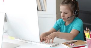 Little girl in headphones is typing on computer keyboard and speaking into microphone 4k movie