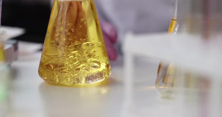 Liquid is added flask with yellow oily liquid carrying out chemical experiment Royalty-Free Stock Footage #1106038405